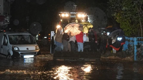 İstanbul’da sağanak sonrası su basan yolda araçlar ve şemsiyeli kişiler