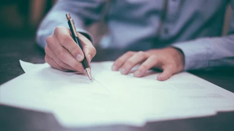 Sigorta işlemleri kapsamında belge üzerinde yazı yazan bir kişinin elleri