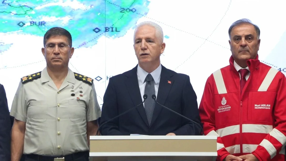 İstanbul Valisi Davut Gül, afet açıklaması sırasında kürsüde; yanında üniformalı bir yetkili ve kırmızı yelekli bir görevli bulunuyor.