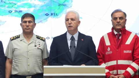 İstanbul Valisi Davut Gül, afet açıklaması sırasında kürsüde; yanında üniformalı bir yetkili ve kırmızı yelekli bir görevli bulunuyor.