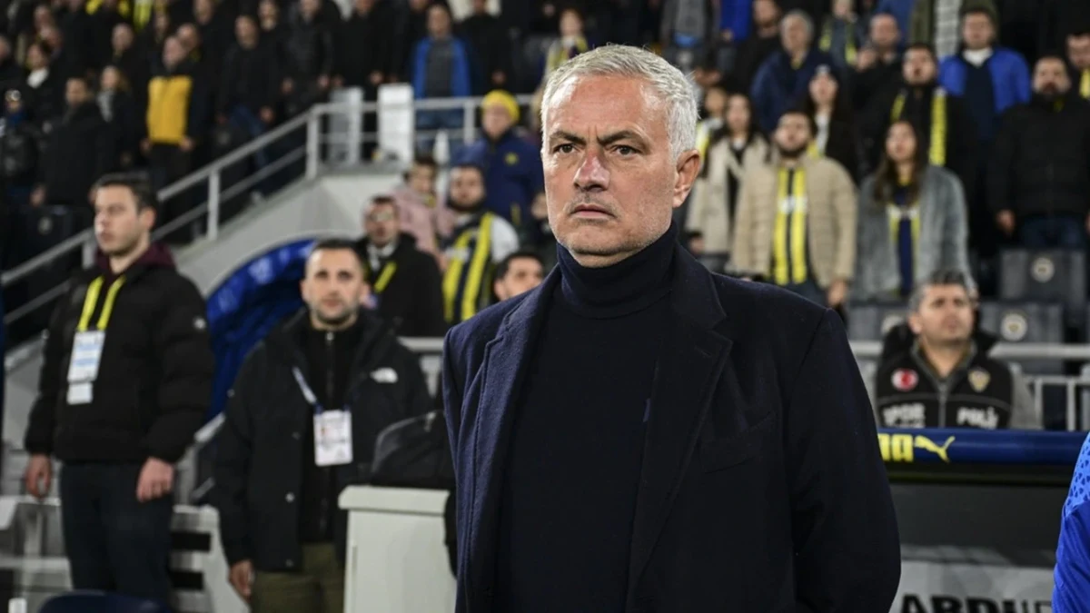 Jose Mourinho, tribünlerin önünde siyah kıyafetleriyle ayakta duruyor.