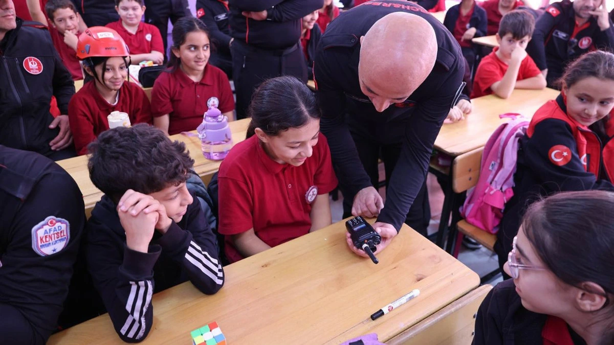 Arama kurtarma görevlisi öğrencilere acil durum düdüğünü gösteriyor
