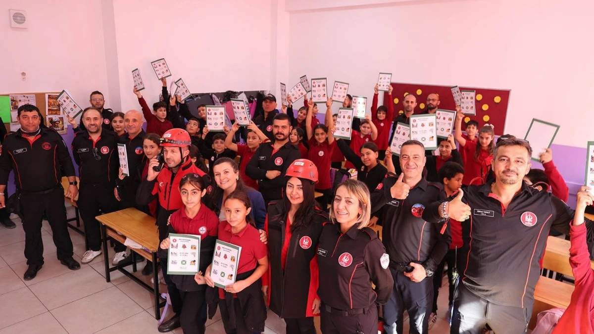 Arama kurtarma ekibi ve öğrenciler afet temalı kitaplarla poz veriyor