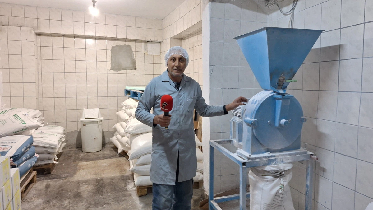 Pudra şekeri üretim makinesinin yanında duran işletme çalışanı