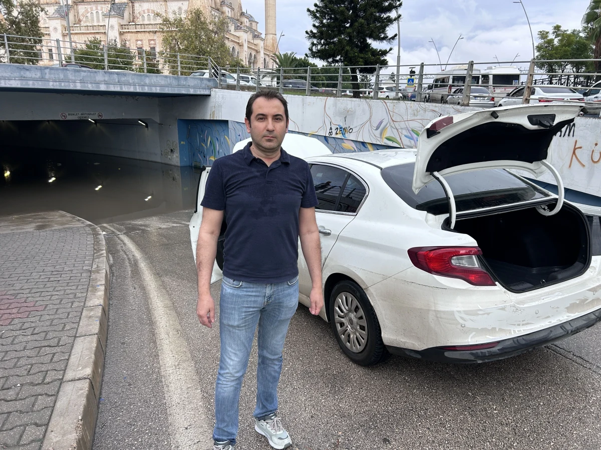 Beyaz aracın yanında duran bir kişi ve açık bagaj