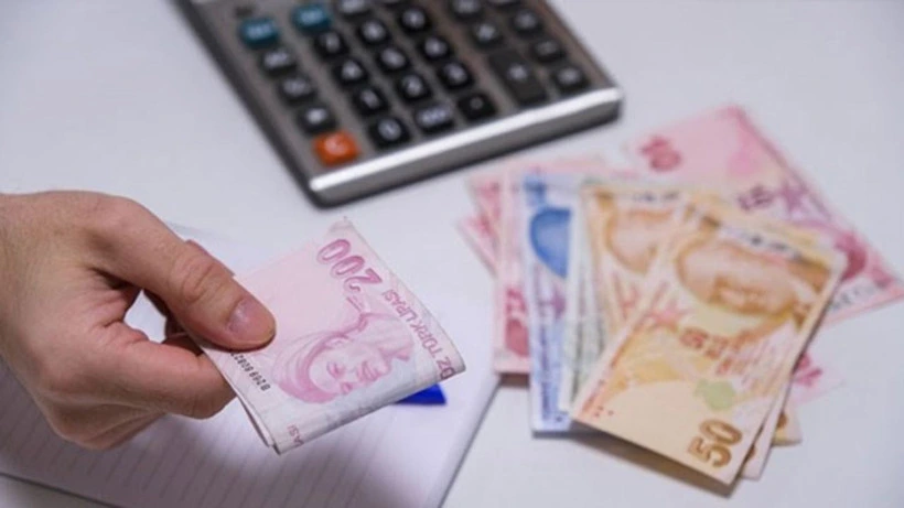 Bir kişinin Türk lirası banknotlarını saydığı, yanında hesap makinesi bulunan masa