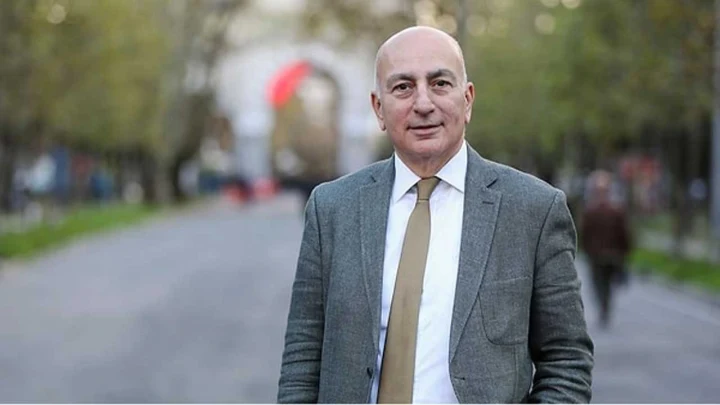 Mahfi Eğilmez, gri takım elbise ve kravatla açık havada