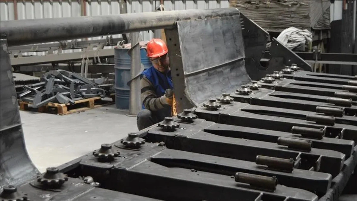Sanayi tesisinde metal parçalar üzerinde çalışan işçi