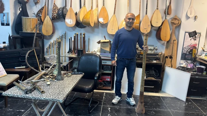 Saz ustası Cengiz Erdoğan, atölyesinde yaptığı 1 metre 35 santimetrelik zurnanın yanında duruyor.