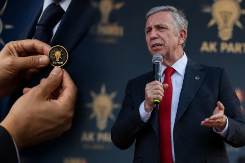 Mansur Yavaş konuşurken, ön planda AK Parti rozetini tutan eller