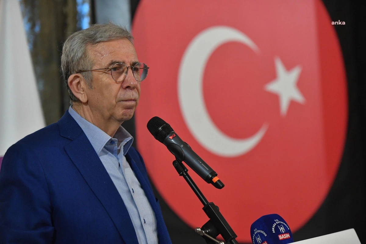 Mansur Yavaş, mikrofon önünde konuşma yapıyor; arka planda Türk bayrağı görülüyor.