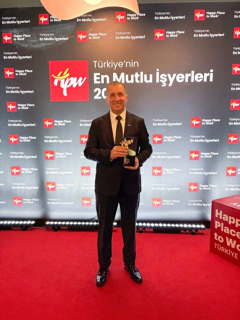 Maya Okulları temsilcisi ödülünü etkinlik fonu önünde tutuyor