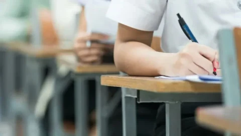 Sınıfta sırasına oturmuş öğrenci yazılı sınav kağıdına cevap yazıyor