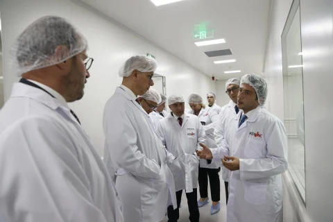 Beyaz önlük ve bone giyen görevliler Keyvac tesisinin koridorunda bir arada