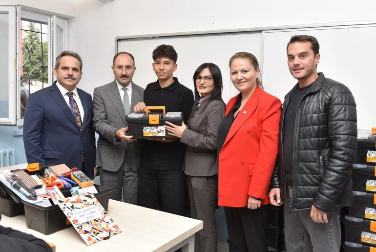 Bir öğrenciye elektrik alanında kullanılacak uygulama kiti sunan temsilciler