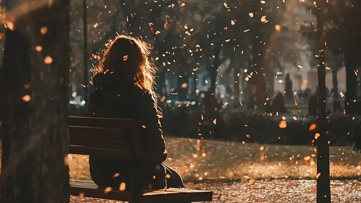 Sonbaharda parkta bir bankta oturan kişi