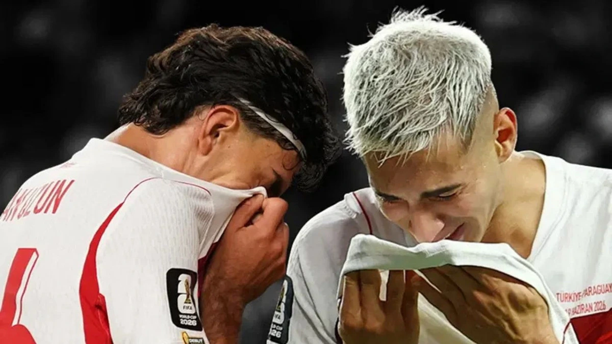 Millî takım forması giyen iki futbolcu başlarını eğmiş durumda