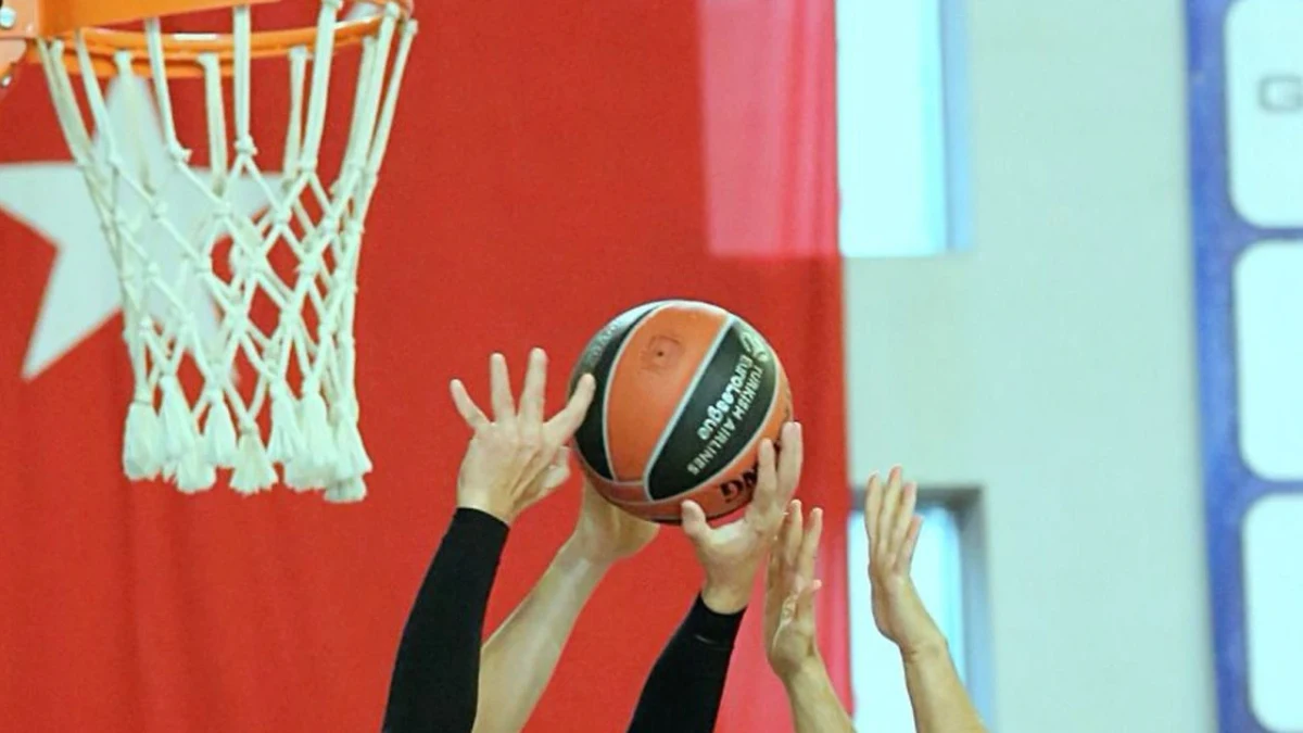 Basketbol potası önünde topa uzanan oyuncular