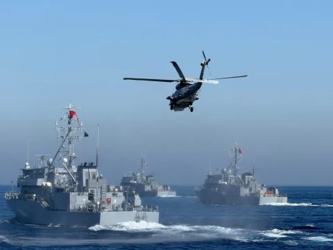 Denizde seyreden askeri gemilerin üzerinde uçan bir helikopter