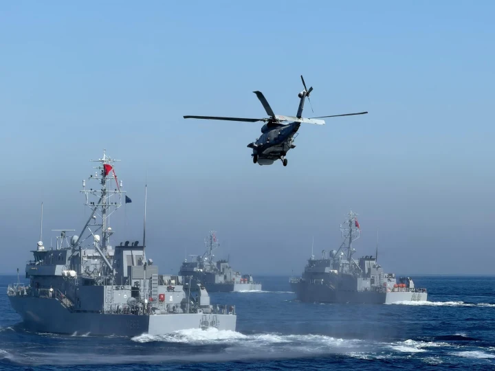 Denizde seyreden askeri gemilerin üzerinde uçan bir helikopter