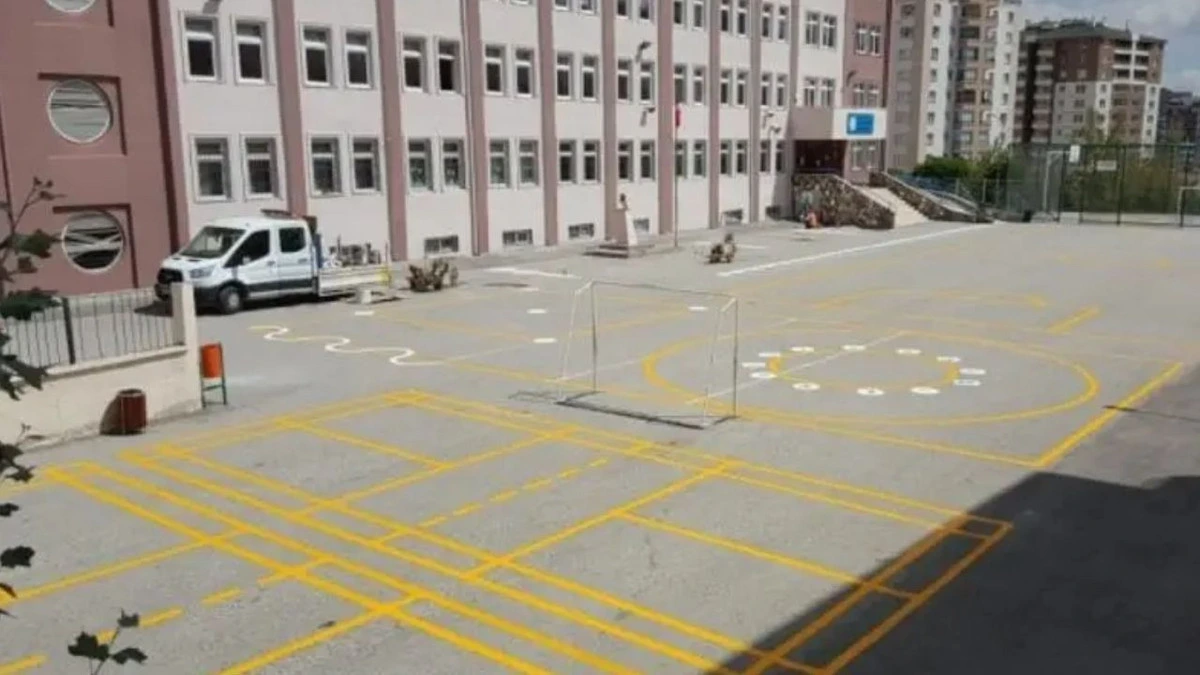 Okul binasının önündeki açık alanda güvenlik şeridi ve işaretlemeler görülüyor.