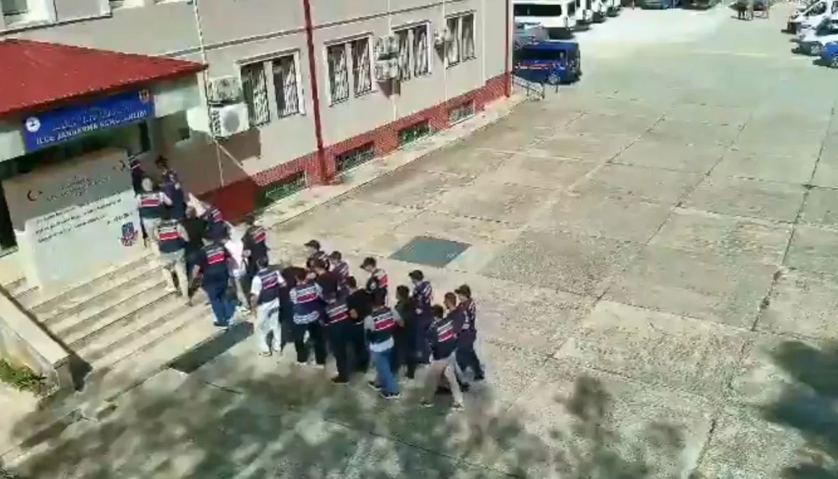 Jandarma ekipleri, gözaltına alınan şüphelileri bir binadan çıkarıyor.