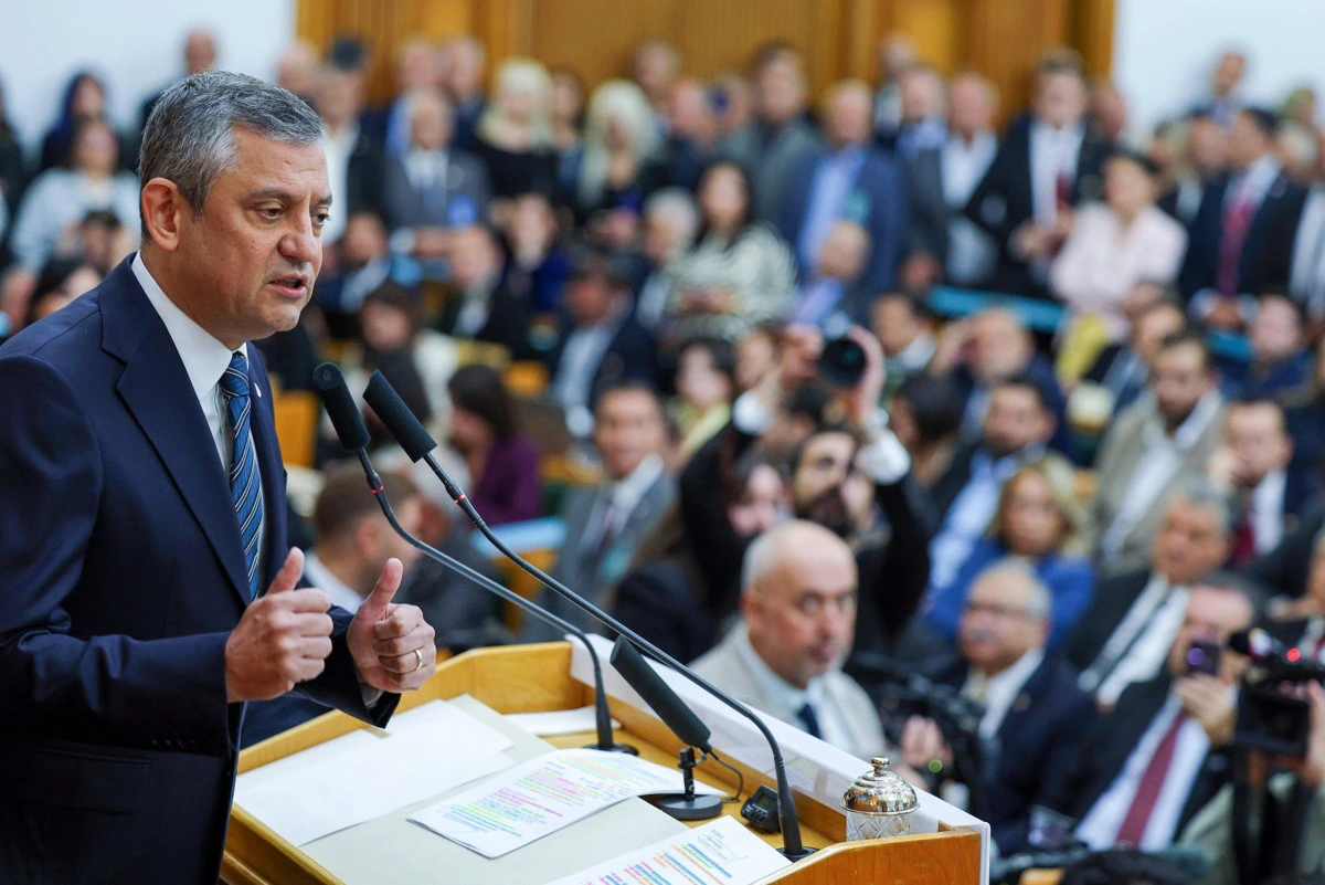 Özgür Özel, kalabalık bir salonda kürsüden konuşuyor