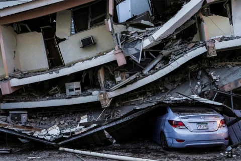 Depremde hasar gören binanın çöken katlarının altında kalan otomobil