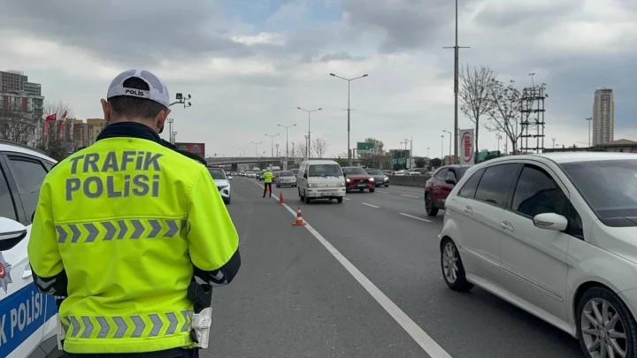 Trafik polisinin yol kenarında durduğu ve araçların ilerlediği şehir yolu