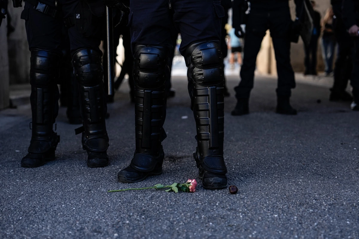 Yerdeki çiçeğin yanında duran çevik kuvvet polislerinin bacakları