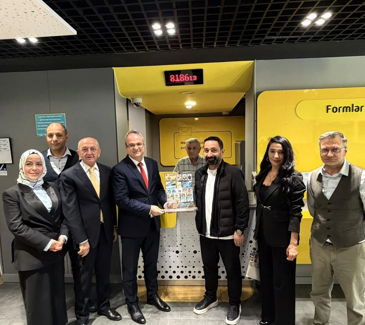 PTT şubesinde kuruluş yıl dönümü dolayısıyla pasta önünde duran çalışanlar