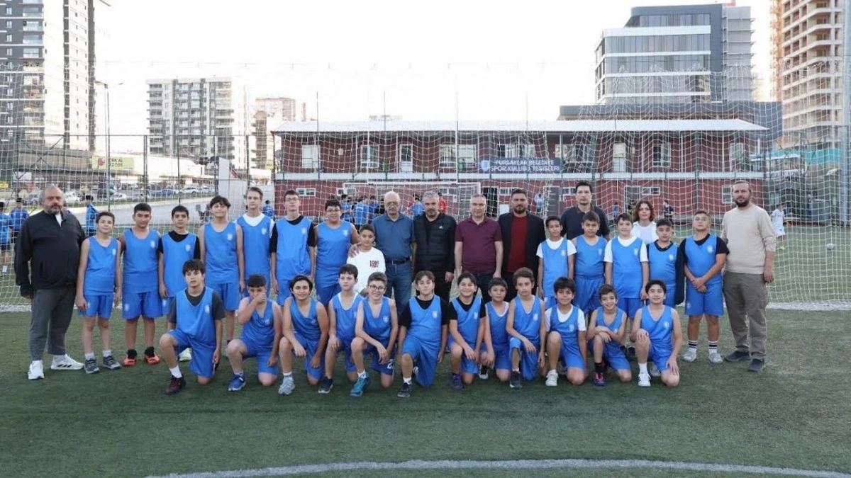 Mavi formalarıyla sahada bulunan genç sporcular ve kulüp temsilcileri