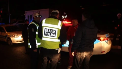 Gece saatlerinde trafik polisleri bir aracın yanında denetim yapıyor