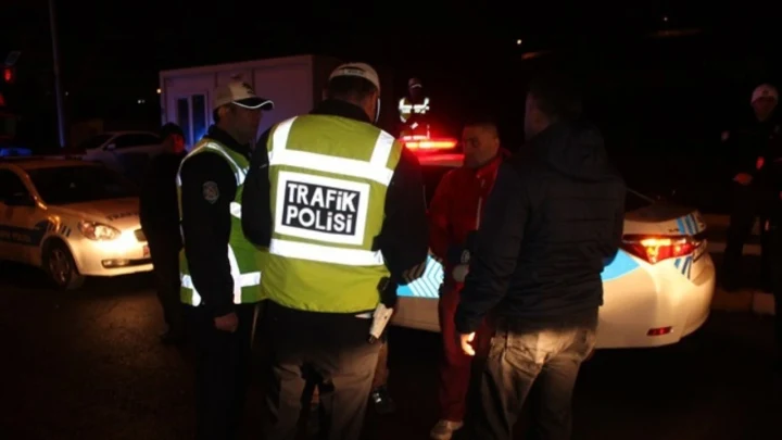 Gece saatlerinde trafik polisleri bir aracın yanında denetim yapıyor