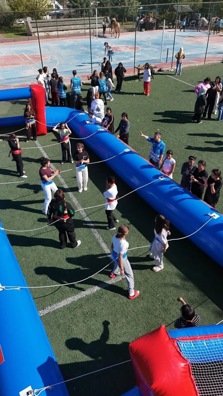 Çocuklar ve yetişkinler şişme oyun parkurunda etkinliğe katılıyor