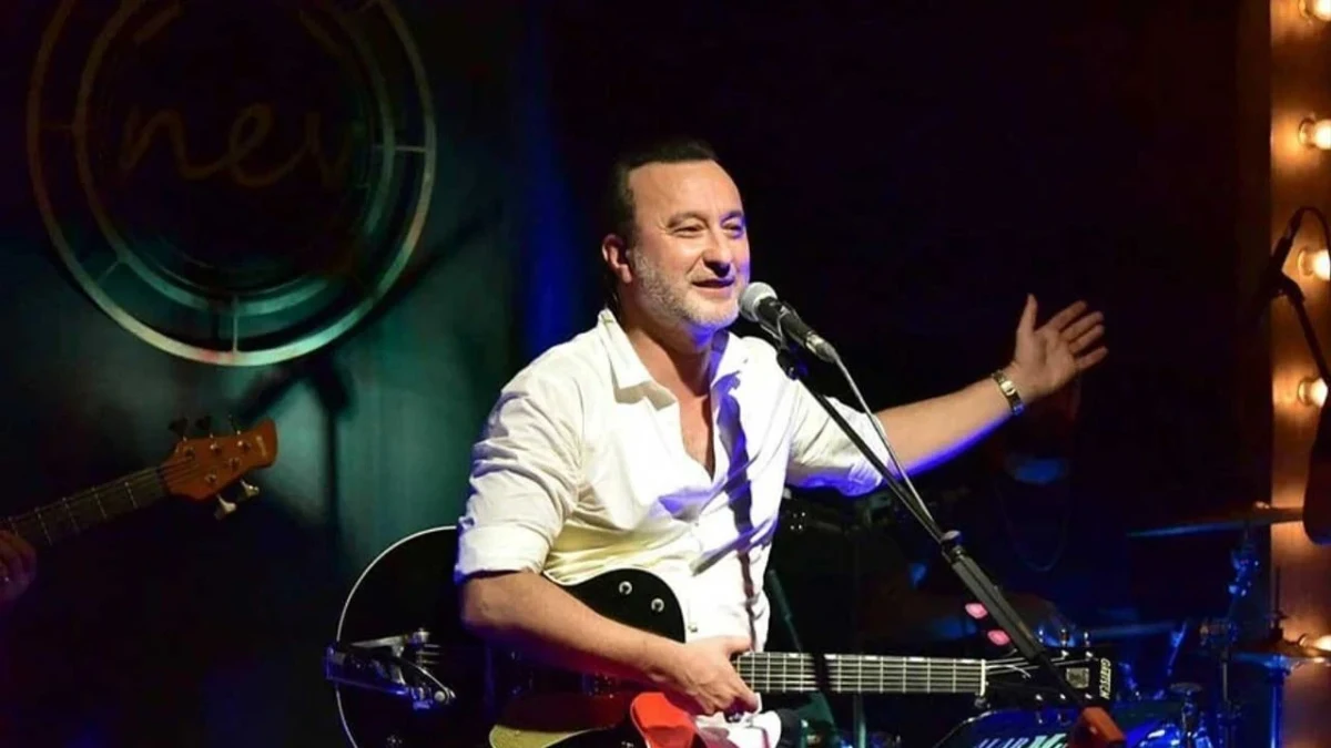 Şarkıcı Nev, gitarıyla sahnede performans sergiliyor.