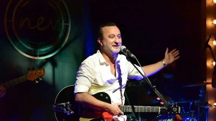 Şarkıcı Nev, gitarıyla sahnede performans sergiliyor.