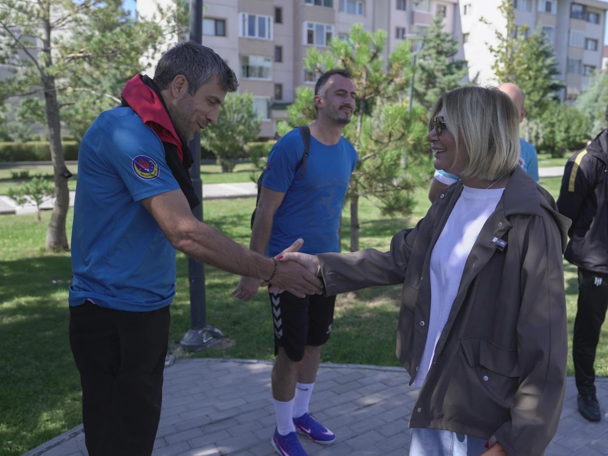 Seda Dilber, spor kıyafetli bir katılımcıyla tokalaşıyor; başka bir sporcu yanlarında duruyor.