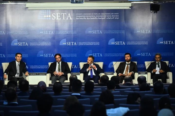 SETA’nın mavi logolu sahnesinde oturan beş panelist ve konferansı izleyen katılımcılar