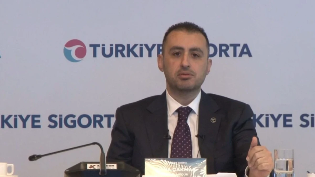 Türkiye Sigorta logosunun önünde oturan Taha Çakmak