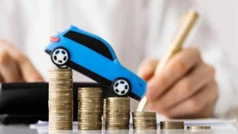 Madeni para yığınlarının üzerinde duran oyuncak otomobil ve hesaplama yapan bir kişi