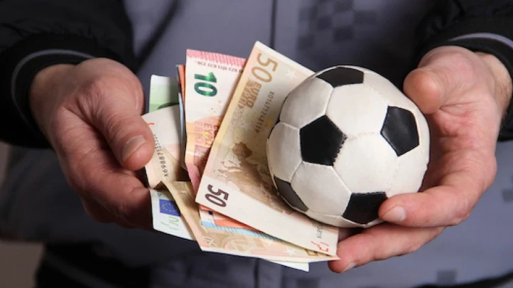 Bir kişinin elinde futbol topu ve banknotlar