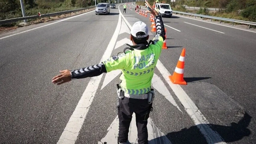 Trafik görevlisi, konilerle belirlenen yolda araçları yönlendiriyor.