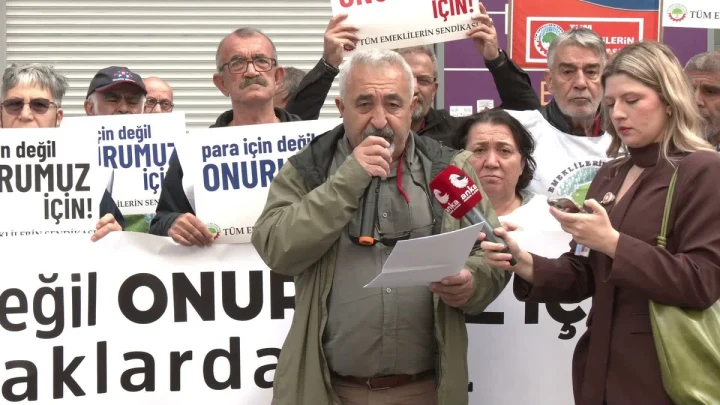 Tüm Emeklilerin Sendikası üyeleri açıklama sırasında pankartlar taşırken Adem Çiftçi mikrofonla konuşuyor.