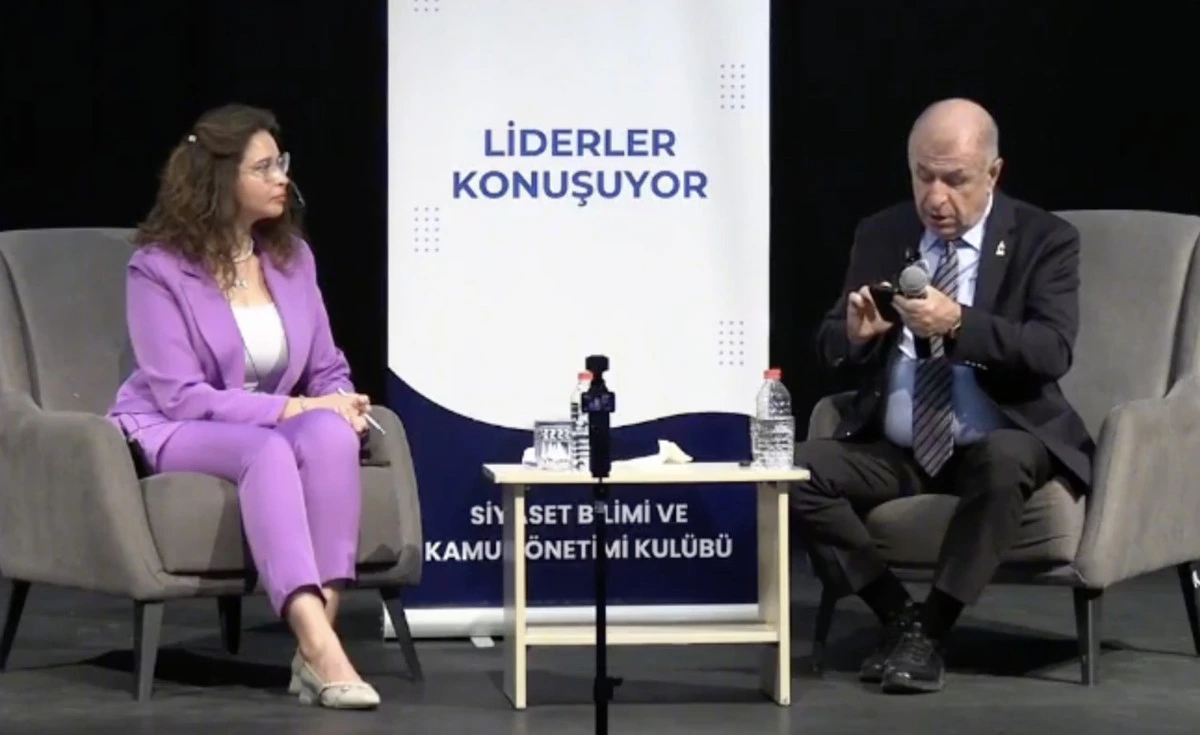 Bir etkinlikte konuşan Ümit Özdağ ve yanında oturan kadın