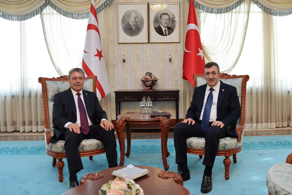 Ünal Üstel ve Cevdet Yılmaz, Türk ve KKTC bayraklarının önünde koltuklarda oturuyor