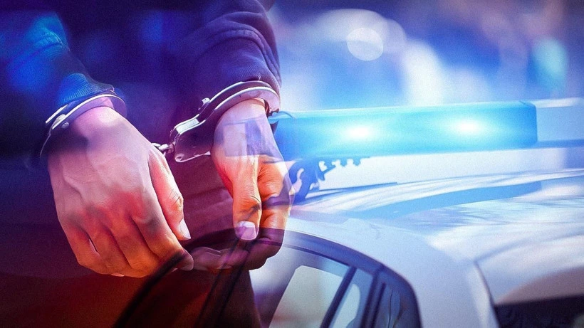 Kelepçeli şüpheli ve polis aracının ışıkları