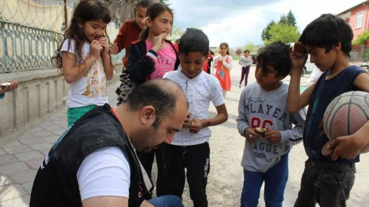 Yasin Oyanık, sokakta çocuklara yardım dağıtıyor.