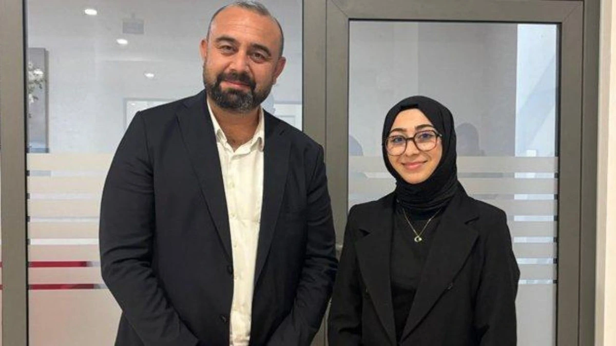 Yasin Oyanık, başörtülü bir kadınla yan yana duruyor.