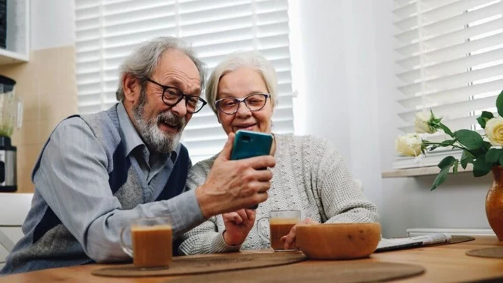 Bir yaşlı çift akıllı telefondaki ekrana birlikte bakıyor